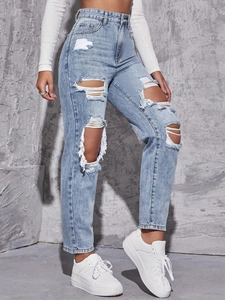 Detail of high waisted light blue jeans with heavy distressed rip and frayed edges