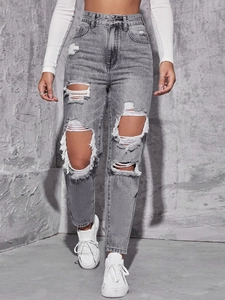 Detailed view of high-waist straight jeans with large distressed rips and acid wash finish