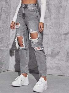 Detail of ripped grey high-waisted jeans featuring distressed cut-outs with white frayed edges