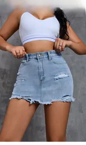 Detail shot of light blue distressed denim skirt with high-waisted cut and raw hem finish