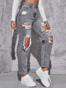 Detail showing distressed rip textures and frayed edges on high waist gray denim jeans