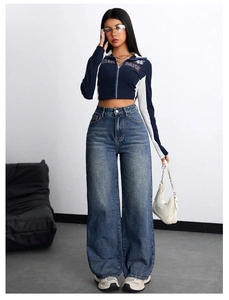Detail of high waisted wide leg jeans paired with a cropped navy zip-up graphic top