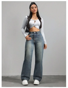 Detail of high waist wide leg denim trousers paired with a cropped knit top on a model