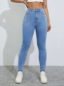Detail der High Waist Skinny Jeans mit dreilagigen Metallketten-Gürteln auf hellblauem Denim