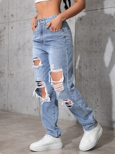 Detail of high waisted wide leg light blue jeans featuring large distressed ripped cutouts
