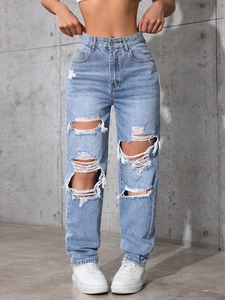 Detailed view of high-waist baggy jeans with distressed ripped knees and light blue denim finish
