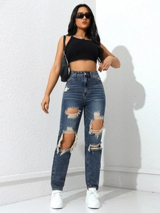 Close-up of high-waisted distressed denim jeans featuring large ripped cutouts and frayed edges
