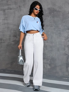 High-waisted white wide-leg denim jeans styled with a cropped blue t-shirt and silver bag