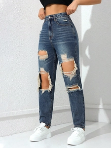Detailed view of high waisted denim jeans with heavy distressed rips and fringe edges