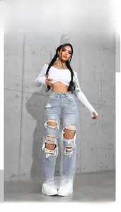 Close-up of ripped light blue high waist jeans with fringe hem and washed texture