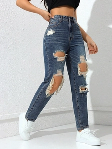 Detail view of frayed distressed denim jeans with large knee rips and fringe edges