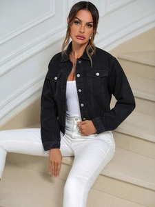 Close-up of black denim jacket with metallic buttons, classic collar and chest pockets