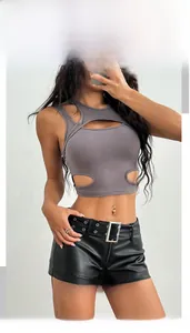 Dettaglio degli shorts in ecopelle nera con cintura a occhielli e top con ritagli