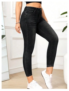 Détail du jean skinny taille haute gris anthracite porté par un mannequin dans un décor moderne