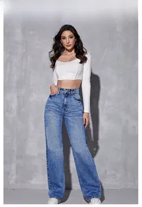 Détail du jean bleu taille haute à jambe large porté avec un haut court blanc pour femme