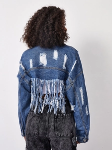 Detail of blue cropped denim jacket featuring back distressing and long tassel fringe