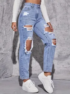 Detailed view of women's distressed light blue straight jeans with ripped knee design