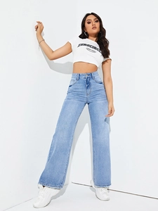 Detail of high-waisted light blue wide-leg denim jeans with natural washed texture finish
