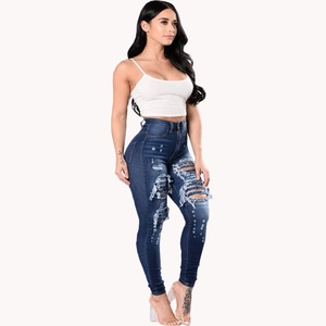 Detail view of high-waist skinny ripped jeans with heavy distressed denim texture