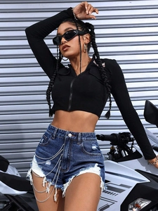 Detail of high-waisted denim shorts with frayed edges and decorative metal chains