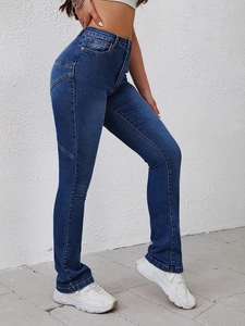 Detail view of high-waisted dark blue flared jeans with contrast orange stitching