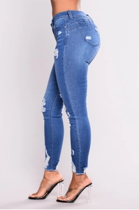 Dettaglio jeans skinny a vita alta con strappi sulle ginocchia e orli sfilacciati