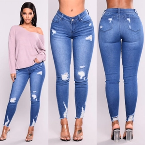 Dettaglio dei jeans a vita alta strappati alle ginocchia con orli sfilacciati