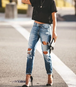 Détail d'un jean skinny bleu avec genoux déchirés et effets de lavage à moustaches