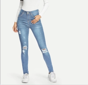Detail showing ripped knees and distressed wash on high waist skinny blue denim jeans