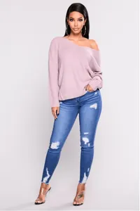 Dettaglio di jeans skinny blu a vita alta con strappi sulle ginocchia e finiture logorate