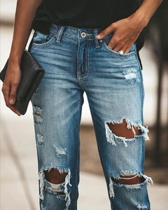 Détail d'un jean bleu moyen délavé avec des genoux déchirés et des bords effilochés