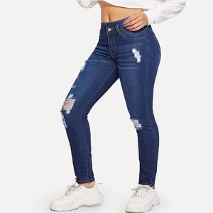 Detail of high waisted distressed skinny jeans with ripped knees and whiskers
