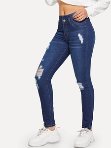 Close-up of high-waisted skinny denim jeans with distressed ripped detailing at the knees