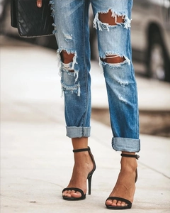 Gros plan sur un jean skinny bleu clair avec genoux déchirés et détails d'ourlets effilochés