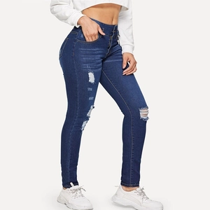 Detail of high-waisted dark blue ripped skinny jeans showing distressed holes and fit