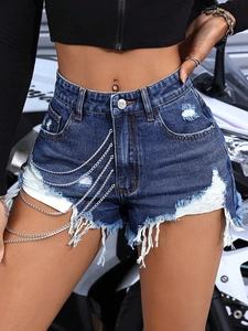 Detail of high-waist distressed denim shorts featuring silver multi-layer metal chains