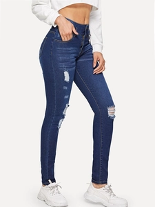 Detail view of high-waisted dark blue skinny jeans with distressed ripped knee patterns
