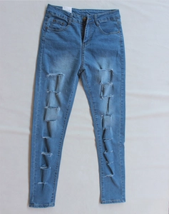 Dettaglio flat lay di jeans azzurri strappati con grandi buchi e design slim fit moderno