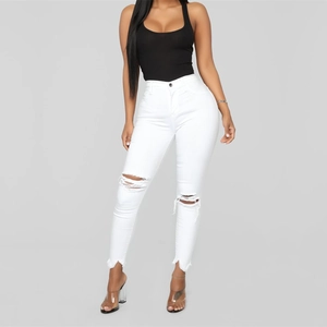 Detail view of white high-waisted distressed skinny jeans with ripped knees and raw hems