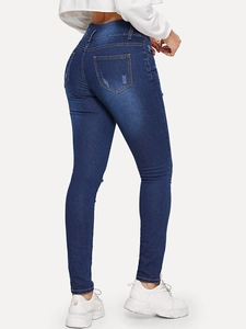 Detail of ripped back pockets and distressed denim on dark blue high waist skinny jeans