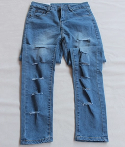 Dettaglio del tessuto denim azzurro e fori orizzontali strappati con effetto usurato
