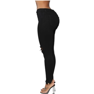 Detail view of women's black slim fit jeans featuring ripped knees and raw hem edges