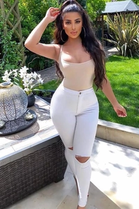 Détail du jean blanc taille haute avec genou déchiré et coupe moulante ajustée