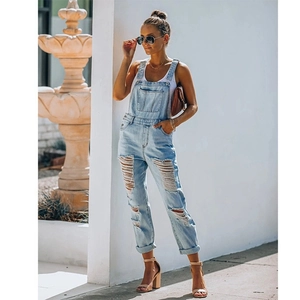 Detail of distressed light blue denim overalls featuring ripped fringe and adjustable straps