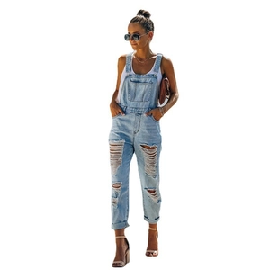 Detail view of light blue distressed denim overalls with ripped knees and rolled cuffs