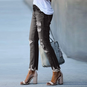 Détail de la texture denim usée et de l'ourlet effiloché sur un jean gris foncé ajusté