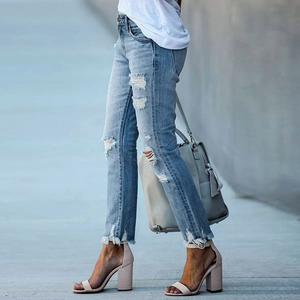 Détail de jean bleu clair avec finitions effilochées et déchirures sur le denim