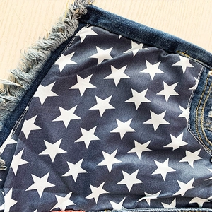 Gros plan détaillé du short en jean bleu avec imprimé étoile et bordures effilochées