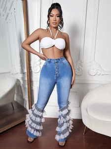 Detail of high waisted blue jeans with multi-layered mesh ruffles on the flared legs
