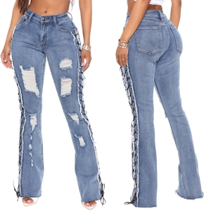 Detail of blue high-waisted distressed jeans with side cross lacing and frayed edges